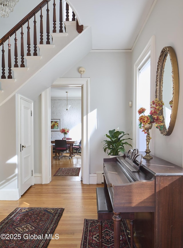 foyer entrance with stairs, light wood finished floors, and crown molding