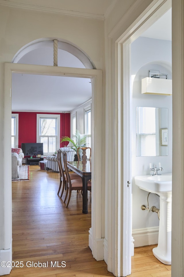 hall featuring arched walkways, ornamental molding, and wood finished floors