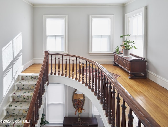 staircase featuring baseboards, crown molding, and plenty of natural light