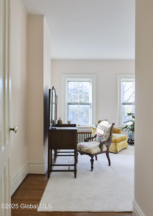 living area with dark wood-type flooring, baseboards, and ornamental molding