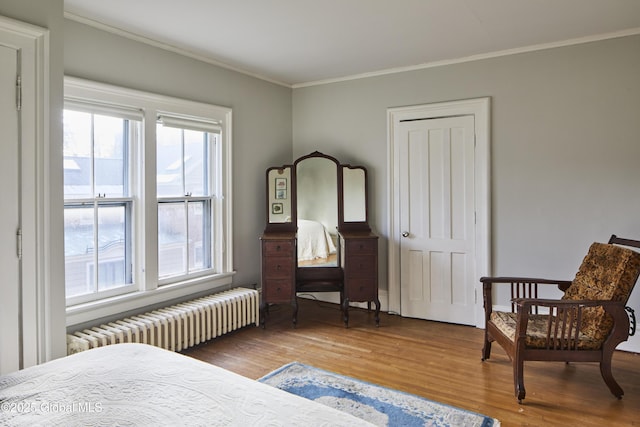 bedroom featuring wood finished floors, ornamental molding, and radiator heating unit