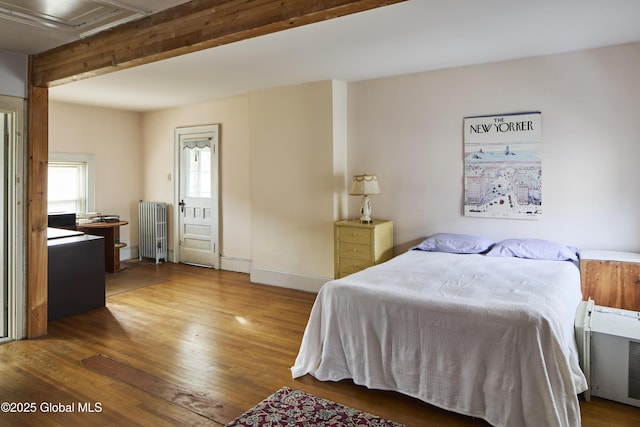 bedroom with baseboards, radiator heating unit, attic access, and wood finished floors