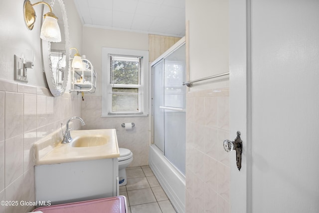 1834 Western Ave, Guilderland, NY 12203 - bathroom with tile patterned flooring, toilet, vanity, enclosed tub / shower combo, and tile walls