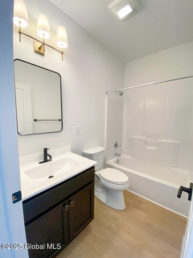 full bathroom with wood finished floors, vanity, toilet, and tub / shower combination