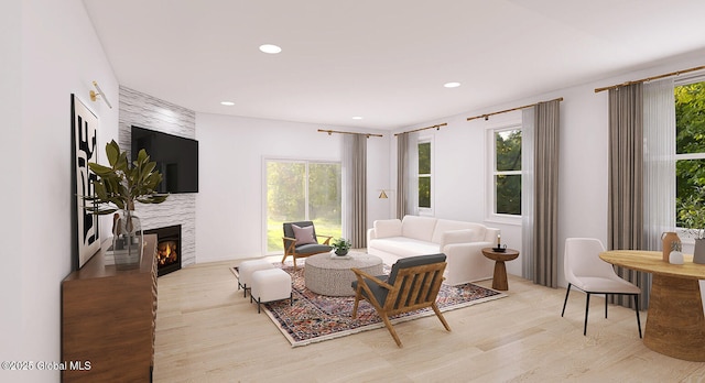 living area with wood finished floors, a warm lit fireplace, plenty of natural light, and recessed lighting