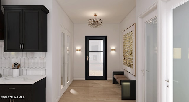 entryway with light wood-type flooring, a chandelier, and baseboards