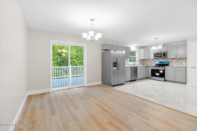 292 Stone Church Rd, Ballston Spa, NY 12020 - kitchen featuring appliances with stainless steel finishes, a chandelier, gray cabinets, light countertops, and backsplash