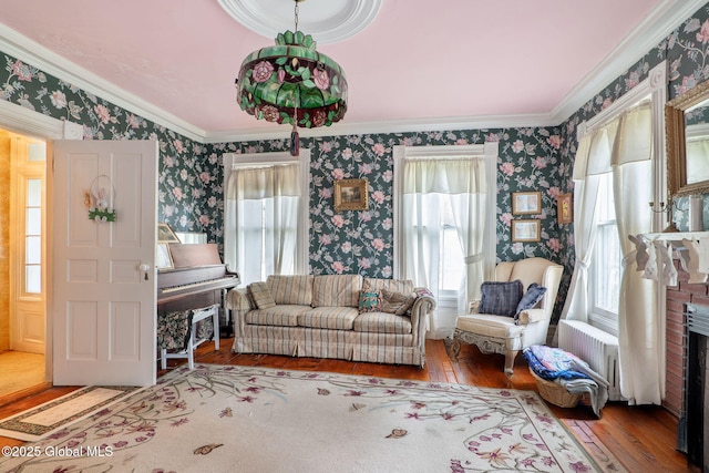12098 Duanesburg Rd, Duanesburg, NY 12053 - living room with wallpapered walls, wood-type flooring, radiator heating unit, crown molding, and a fireplace