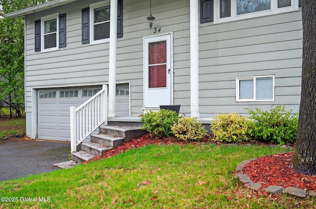 property entrance with an attached garage, driveway, and a yard