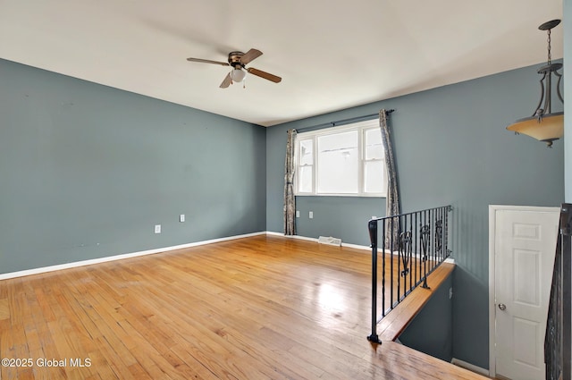 unfurnished room with ceiling fan, hardwood / wood-style floors, and baseboards