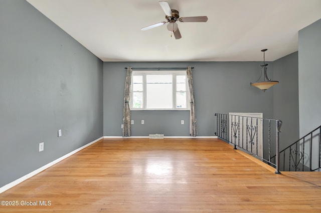 spare room featuring ceiling fan, wood finished floors, and baseboards