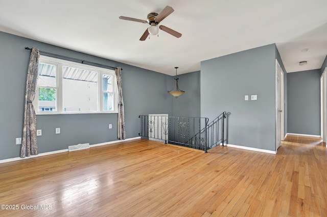 empty room featuring a ceiling fan, hardwood / wood-style floors, and baseboards