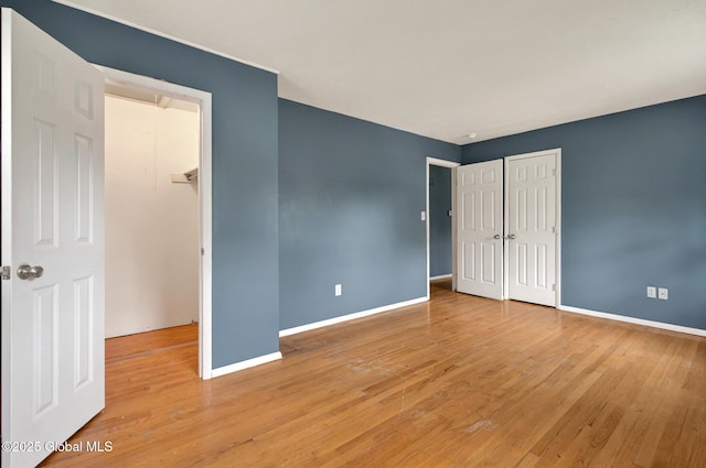 unfurnished bedroom featuring baseboards, light wood-style flooring, and a closet