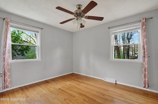 unfurnished room with healthy amount of natural light, wood finished floors, baseboards, and a ceiling fan