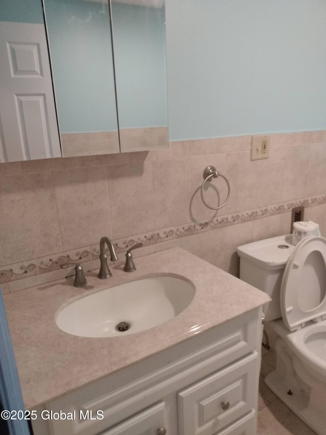 half bathroom featuring vanity, toilet, and tile walls