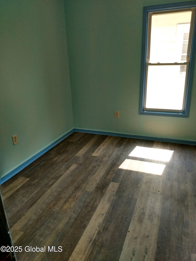 spare room featuring dark wood-type flooring and baseboards
