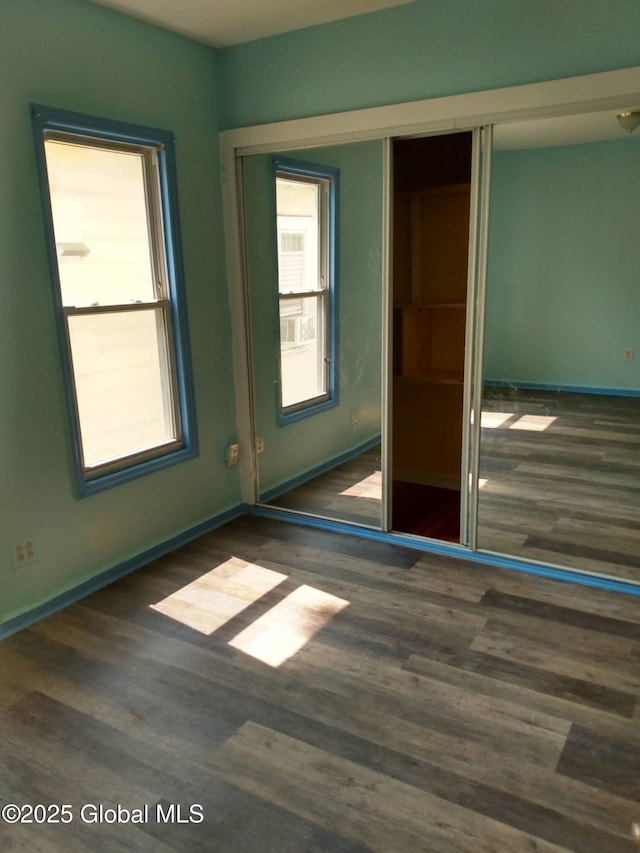 unfurnished bedroom featuring wood finished floors, a closet, and baseboards