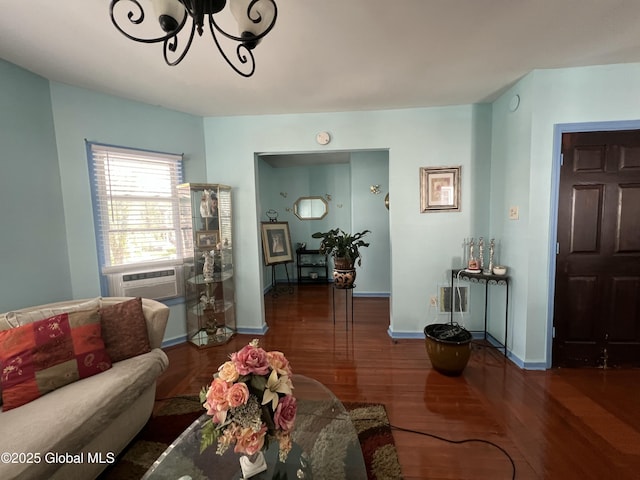 living area featuring wood finished floors, a chandelier, baseboards, and cooling unit