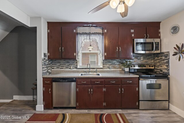 2125 Ferguson St, Rotterdam, NY 12303 - kitchen featuring appliances with stainless steel finishes, a sink, light wood-style floors, tasteful backsplash, and a ceiling fan