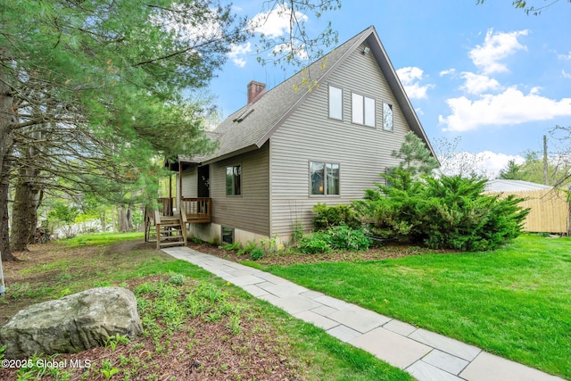 view of side of home featuring a chimney, a lawn, and a shingled roof