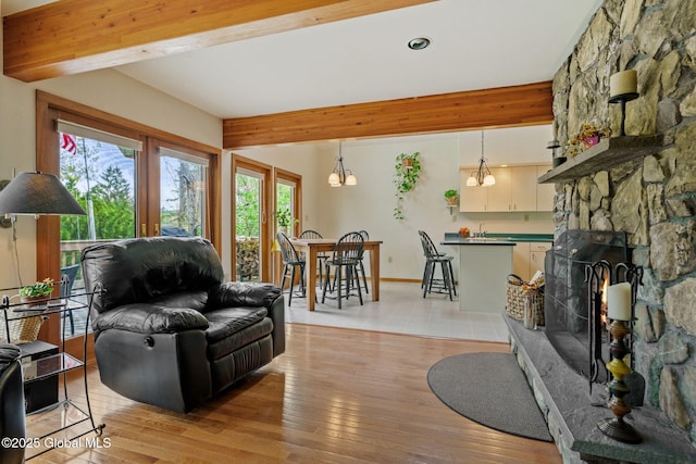 living area with plenty of natural light, beamed ceiling, light wood finished floors, recessed lighting, and a chandelier