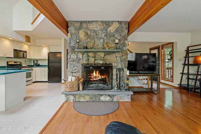 living room with light wood finished floors, a fireplace, beam ceiling, and baseboards