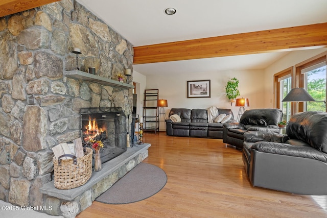 living area featuring wood finished floors, a fireplace, and beam ceiling