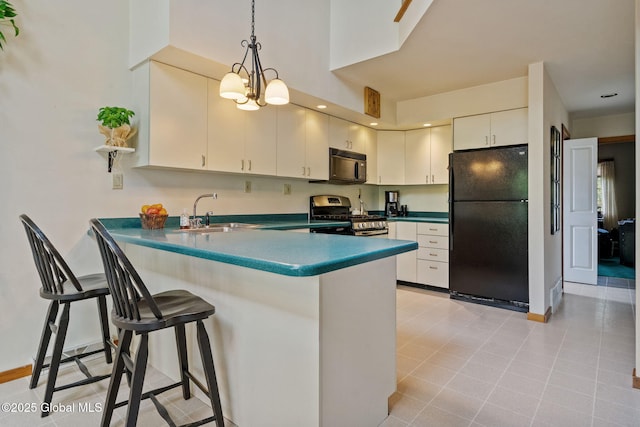 kitchen with black appliances, a sink, a peninsula, dark countertops, and hanging light fixtures