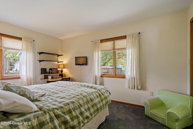 bedroom featuring multiple windows, dark carpet, and baseboards