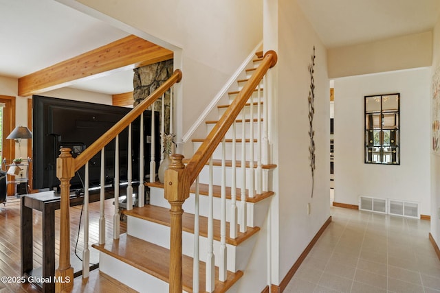 staircase featuring healthy amount of natural light, baseboards, and beam ceiling