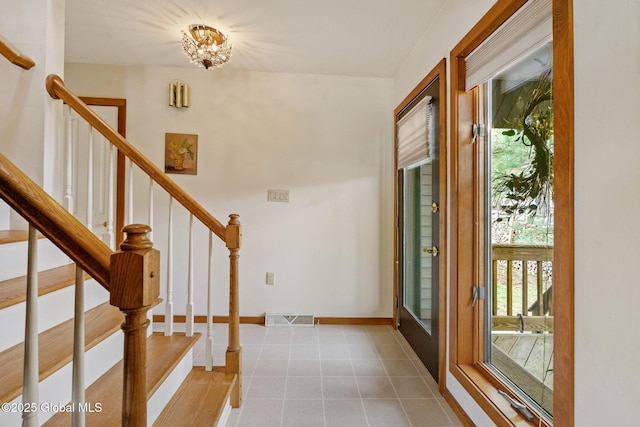 entryway featuring a chandelier, stairs, and baseboards