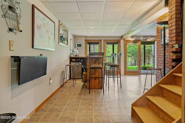 dining area featuring a drop ceiling, baseboards, and stairs