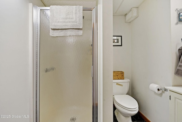 bathroom featuring a stall shower, toilet, vanity, and baseboards