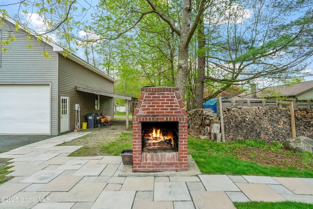 view of patio / terrace with an outdoor brick fireplace and a garage