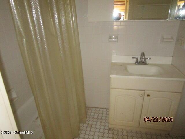 bathroom with vanity, tile walls, and a shower with curtain