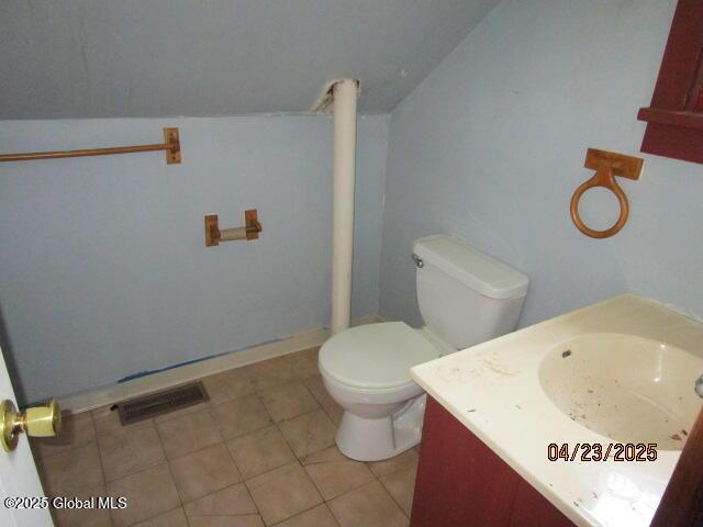 bathroom with vanity, toilet, tile patterned floors, and vaulted ceiling