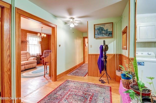 corridor featuring washer / dryer, wood finished floors, a wainscoted wall, and a chandelier