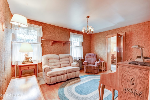 living room with wood finished floors, a chandelier, radiator heating unit, and wallpapered walls