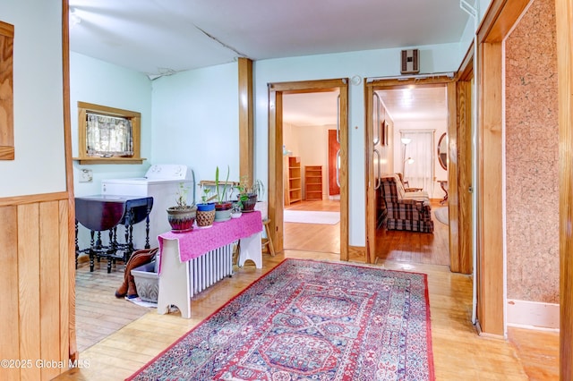 hallway with wood finished floors and a wainscoted wall