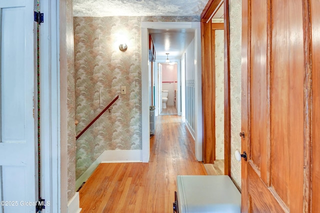 hallway with wallpapered walls, light wood-type flooring, and baseboards