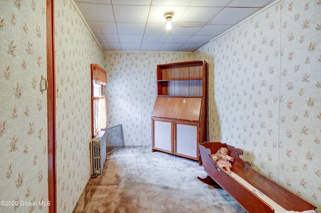 carpeted spare room with radiator and wallpapered walls