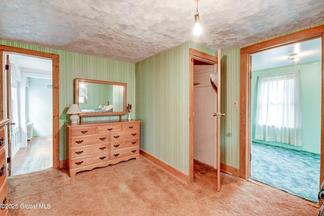 bedroom with a closet, light colored carpet, wallpapered walls, and baseboards