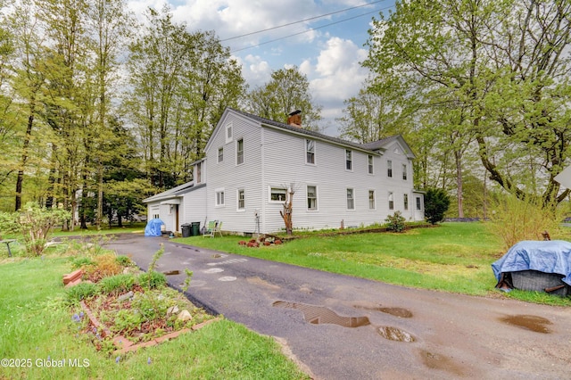 view of home's exterior with a chimney and a lawn
