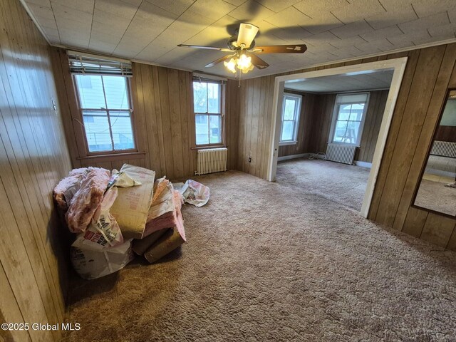 1220 5th Ave, Watervliet, NY 12189 - misc room featuring radiator heating unit, carpet, healthy amount of natural light, wood walls, and a ceiling fan