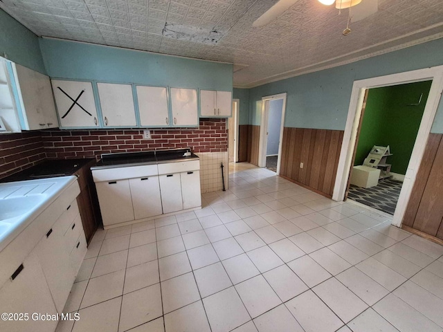 1220 5th Ave, Watervliet, NY 12189 - kitchen featuring wainscoting, white cabinetry, wooden walls, and light tile patterned floors