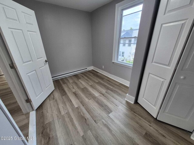 1220 5th Ave, Watervliet, NY 12189 - unfurnished bedroom with baseboard heating, wood finished floors, and baseboards
