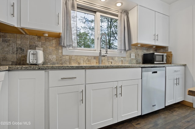 kitchen featuring stainless steel dishwasher, white cabinetry, dark wood finished floors, light stone counters, and backsplash