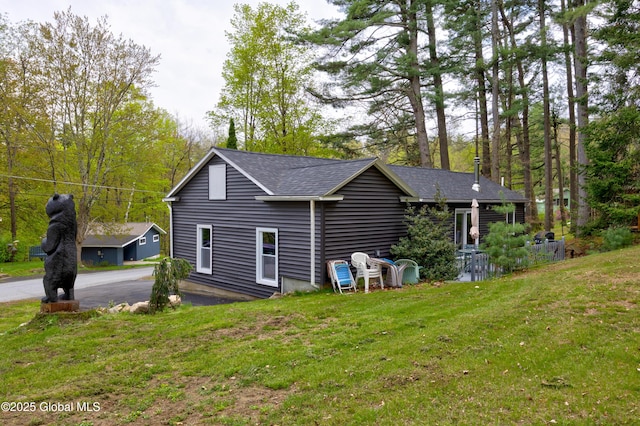 back of property with a yard and a shingled roof