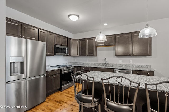 19 Pasture Pl, Ballston, NY 12019 - kitchen featuring stainless steel appliances, a sink, dark brown cabinets, a breakfast bar area, and light stone countertops