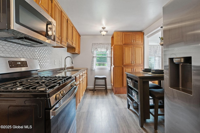 1841 Lenox Rd, Schenectady, NY 12308 - kitchen with appliances with stainless steel finishes, a sink, light wood finished floors, decorative backsplash, and baseboards
